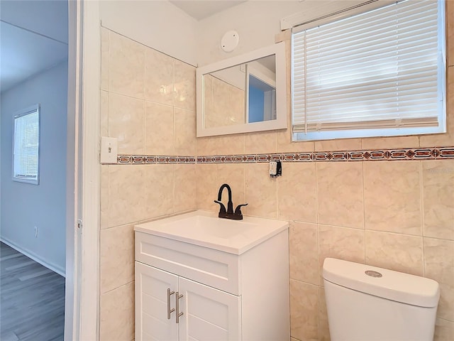 bathroom featuring vanity, tile walls, and toilet