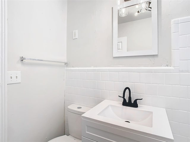 bathroom featuring vanity, toilet, and tile walls