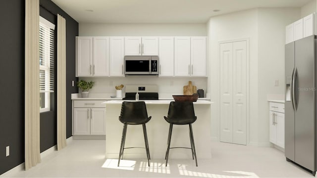 kitchen featuring appliances with stainless steel finishes, white cabinets, a kitchen breakfast bar, a center island, and light tile patterned floors