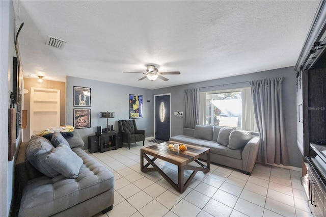 living room with ceiling fan, a textured ceiling, and light tile patterned floors