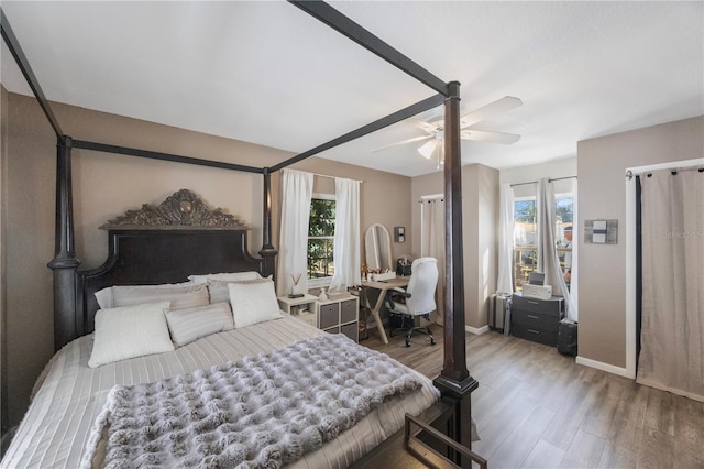 bedroom featuring multiple windows, hardwood / wood-style floors, radiator, and ceiling fan