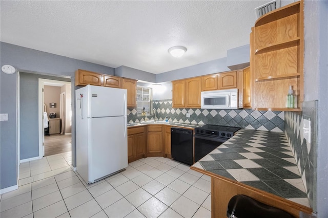 kitchen with sink, light tile patterned floors, white appliances, tile counters, and decorative backsplash