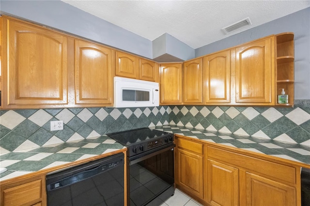 kitchen with tile countertops, backsplash, light tile patterned floors, and black appliances