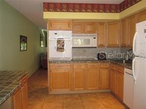 kitchen featuring backsplash, white appliances, and light tile patterned floors