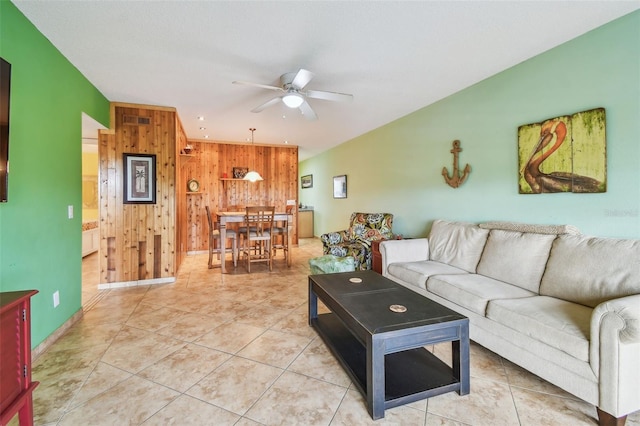 tiled living room with ceiling fan and wooden walls