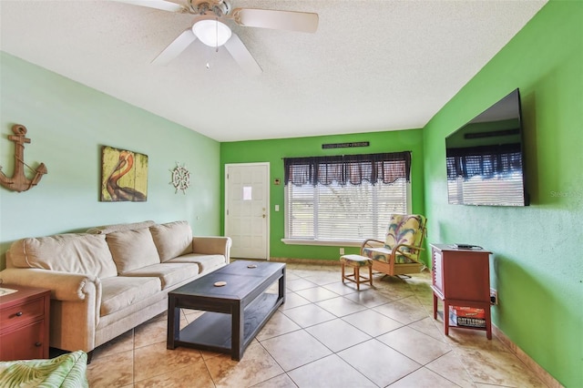 living room featuring ceiling fan, a textured ceiling, and light tile patterned floors