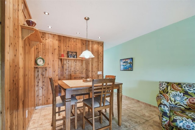 dining space featuring light tile patterned floors and wood walls