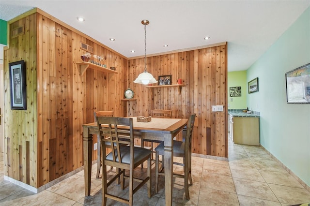 tiled dining room featuring wood walls