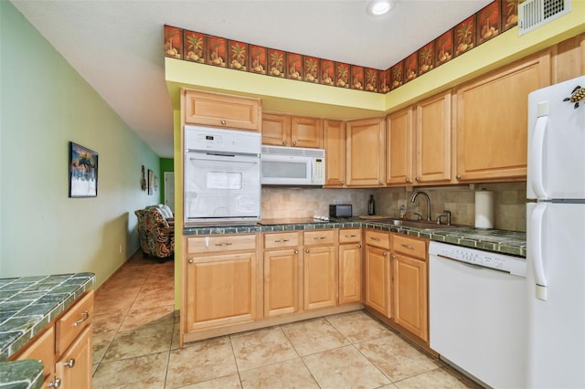 kitchen with sink, light tile patterned floors, backsplash, and white appliances