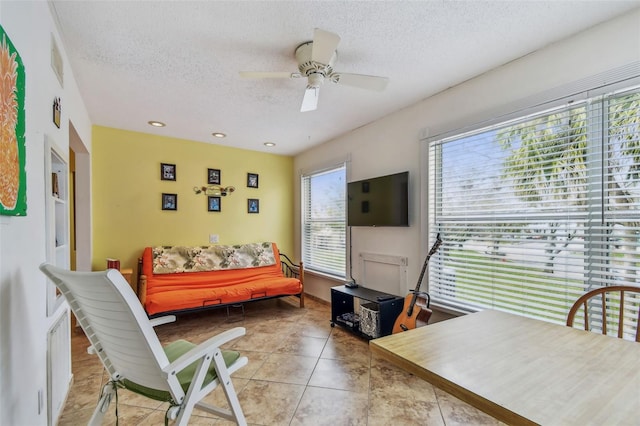 living room featuring ceiling fan, a textured ceiling, and light tile patterned floors
