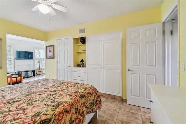bedroom with light tile patterned flooring, ceiling fan, and a textured ceiling