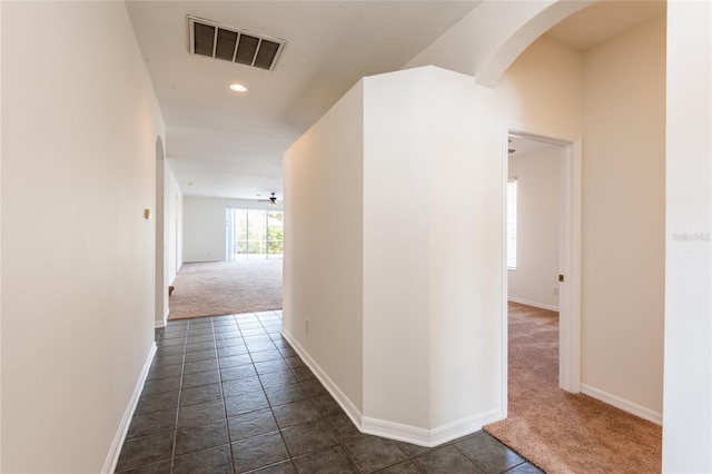 hallway featuring visible vents, baseboards, recessed lighting, arched walkways, and dark colored carpet