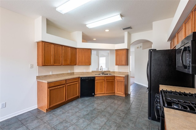 kitchen with visible vents, black appliances, a sink, brown cabinetry, and light countertops