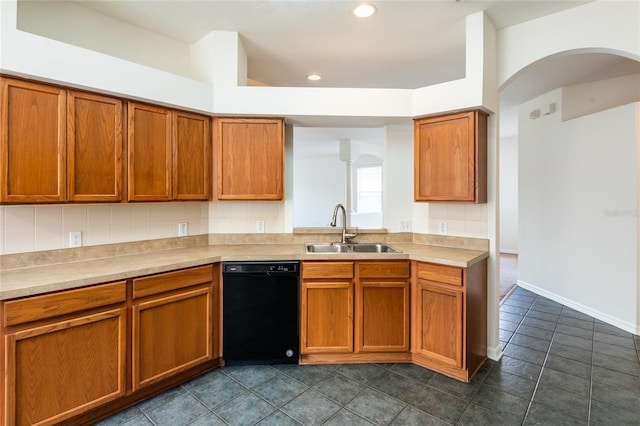 kitchen featuring brown cabinetry, arched walkways, a sink, light countertops, and dishwasher