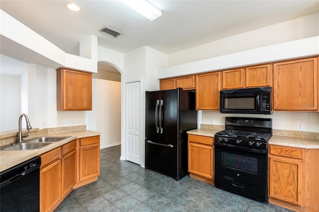 kitchen with visible vents, light countertops, arched walkways, black appliances, and a sink