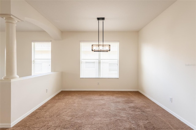 empty room featuring baseboards, carpet flooring, and ornate columns