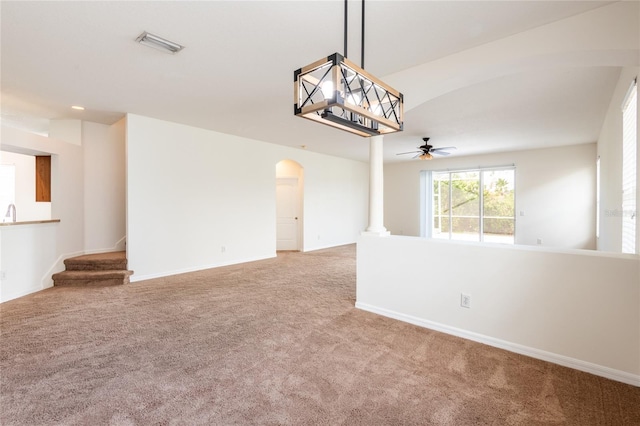 carpeted spare room featuring a ceiling fan, visible vents, arched walkways, and baseboards