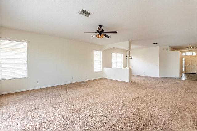 empty room featuring visible vents, baseboards, decorative columns, light carpet, and a ceiling fan