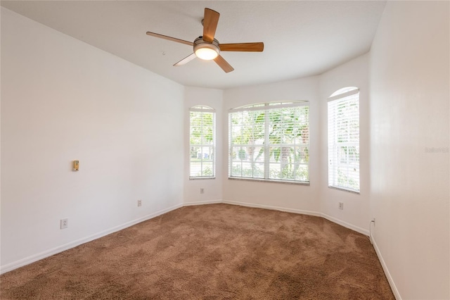 carpeted empty room featuring ceiling fan and baseboards