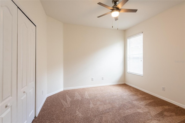 carpeted spare room featuring baseboards and ceiling fan