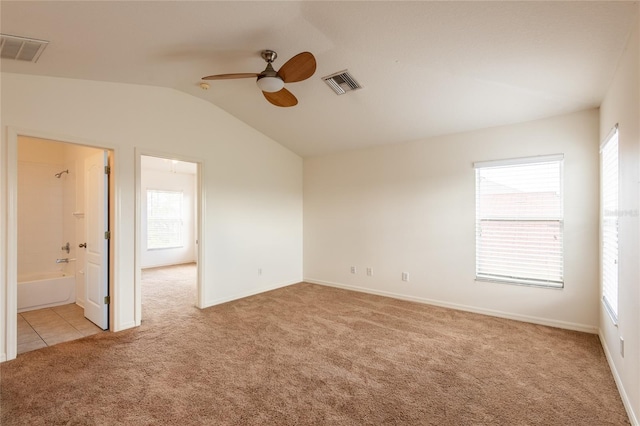 empty room with visible vents, light colored carpet, a ceiling fan, and vaulted ceiling