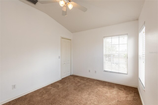 empty room featuring lofted ceiling, baseboards, visible vents, and carpet floors