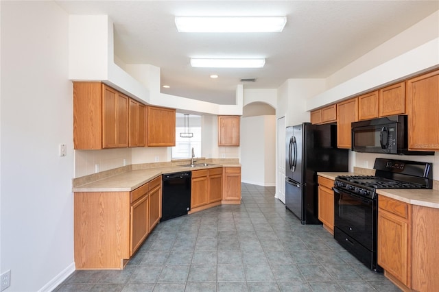 kitchen featuring visible vents, black appliances, a sink, arched walkways, and light countertops