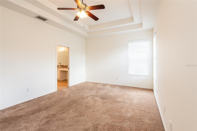 unfurnished room with visible vents, baseboards, light colored carpet, a raised ceiling, and a ceiling fan