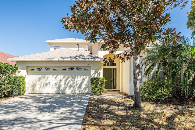 view of front facade featuring a shingled roof, an attached garage, driveway, and stucco siding