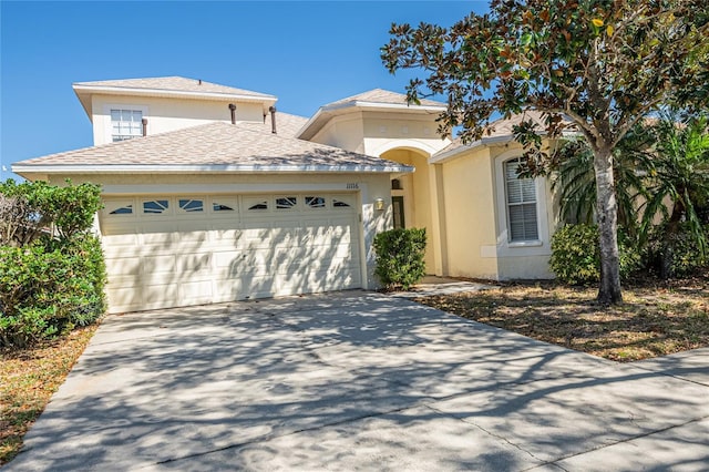 view of front facade featuring stucco siding, driveway, roof with shingles, and an attached garage