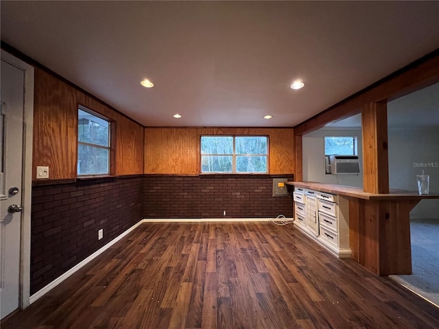 interior space featuring brick wall, dark hardwood / wood-style flooring, a breakfast bar, and kitchen peninsula