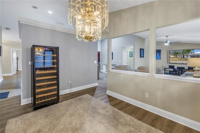 dining space featuring dark wood-type flooring, beverage cooler, ceiling fan with notable chandelier, and vaulted ceiling