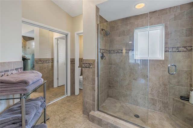 bathroom featuring tile walls, an enclosed shower, tile patterned floors, and toilet