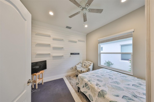 carpeted bedroom with wooden walls, visible vents, baseboards, ceiling fan, and recessed lighting