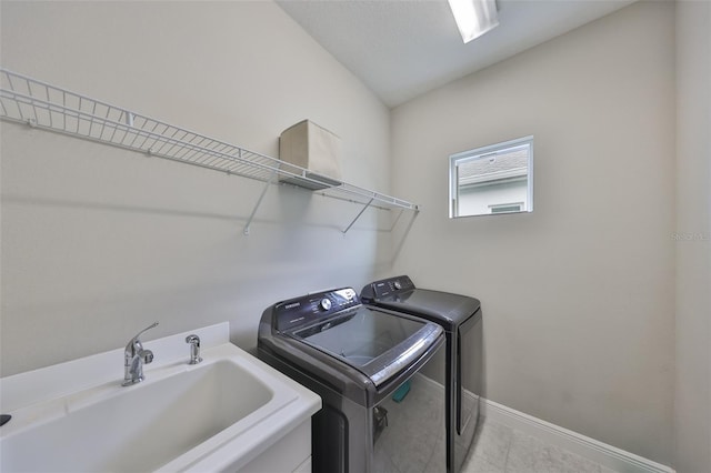 laundry room featuring laundry area, light tile patterned floors, baseboards, washer and clothes dryer, and a sink