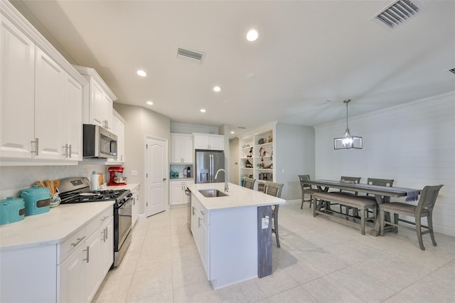 kitchen featuring pendant lighting, a breakfast bar area, appliances with stainless steel finishes, an island with sink, and white cabinets