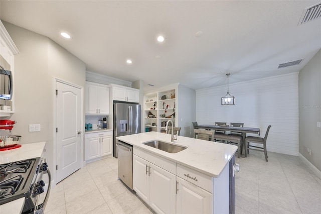 kitchen with an island with sink, decorative light fixtures, stainless steel appliances, white cabinetry, and a sink