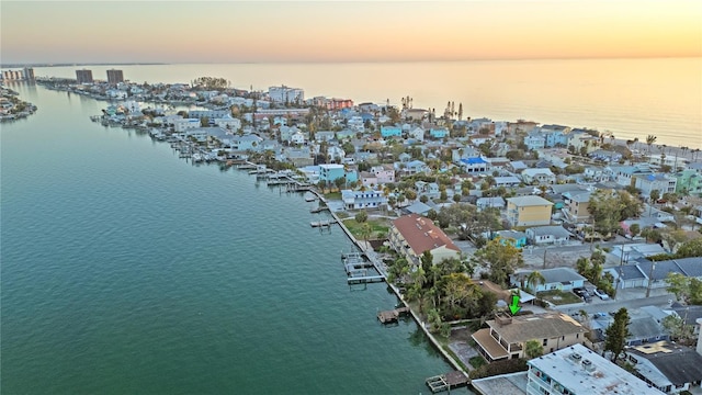 aerial view at dusk featuring a water view