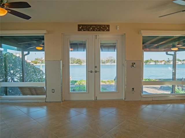 entryway featuring light tile patterned floors, french doors, ceiling fan, and a water view