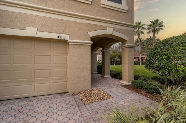 exterior entry at dusk featuring a garage