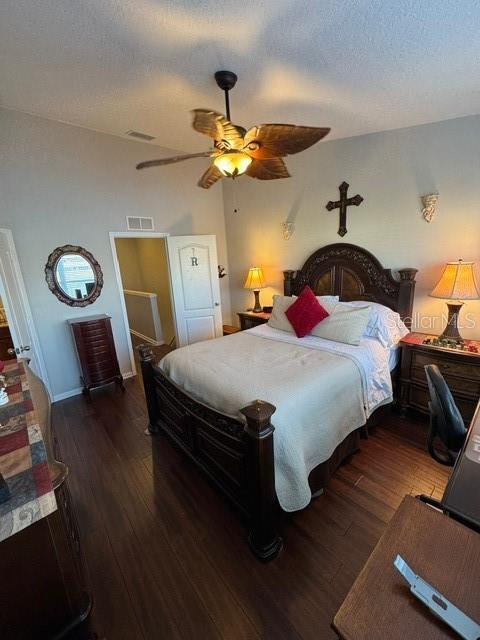 bedroom with ceiling fan, a textured ceiling, and dark hardwood / wood-style flooring