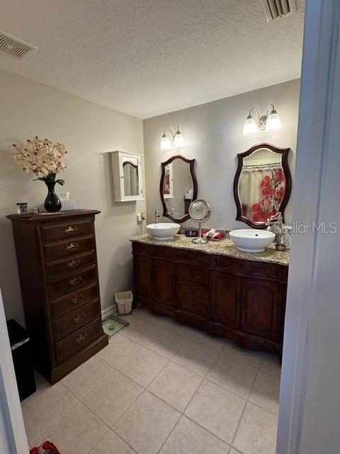 bathroom featuring tile patterned flooring, vanity, and a textured ceiling