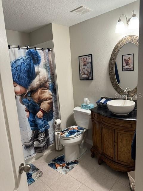 bathroom with tile patterned floors, toilet, vanity, and a textured ceiling