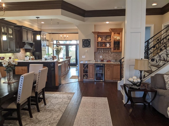 kitchen featuring dark wood-type flooring, ornamental molding, beverage cooler, and hanging light fixtures