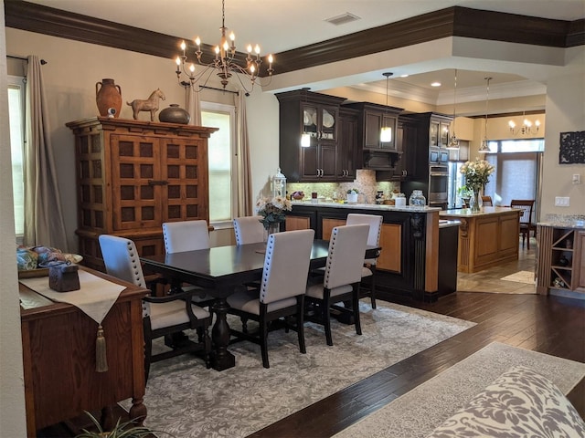 dining space with an inviting chandelier, ornamental molding, and dark hardwood / wood-style floors