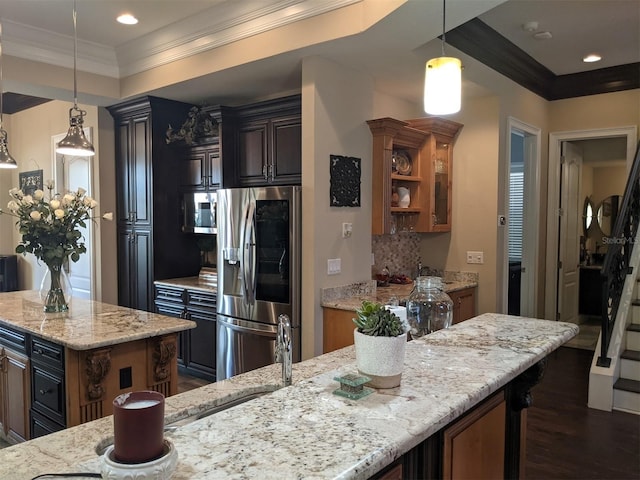 kitchen featuring light stone counters, hanging light fixtures, stainless steel appliances, and a center island