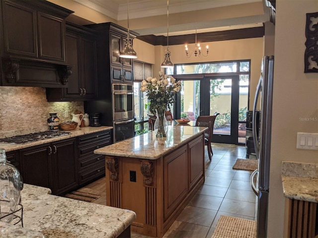 kitchen with stainless steel appliances, a center island, light stone counters, and decorative light fixtures