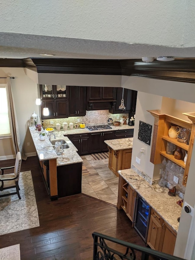 kitchen with sink, a center island, dark brown cabinetry, stainless steel gas cooktop, and dark hardwood / wood-style flooring