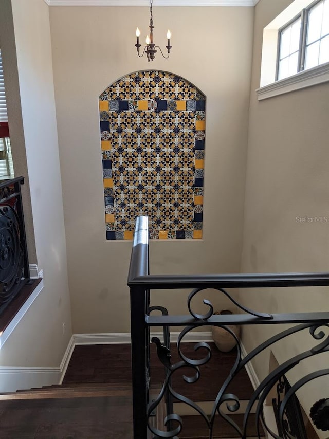 stairway with wood-type flooring and an inviting chandelier