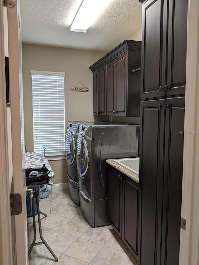 washroom with washer and clothes dryer, cabinets, and a textured ceiling